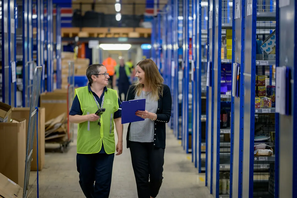 Illustrative stock photograph: Retail warehouse colleagues checking inventory with a barcode scanner and clipboard.