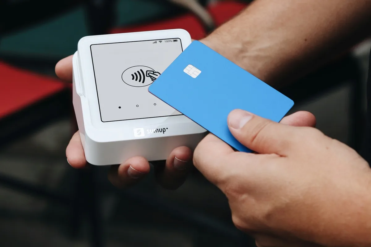 Illustrative stock photograph: Card held over a portable contactless card reader.