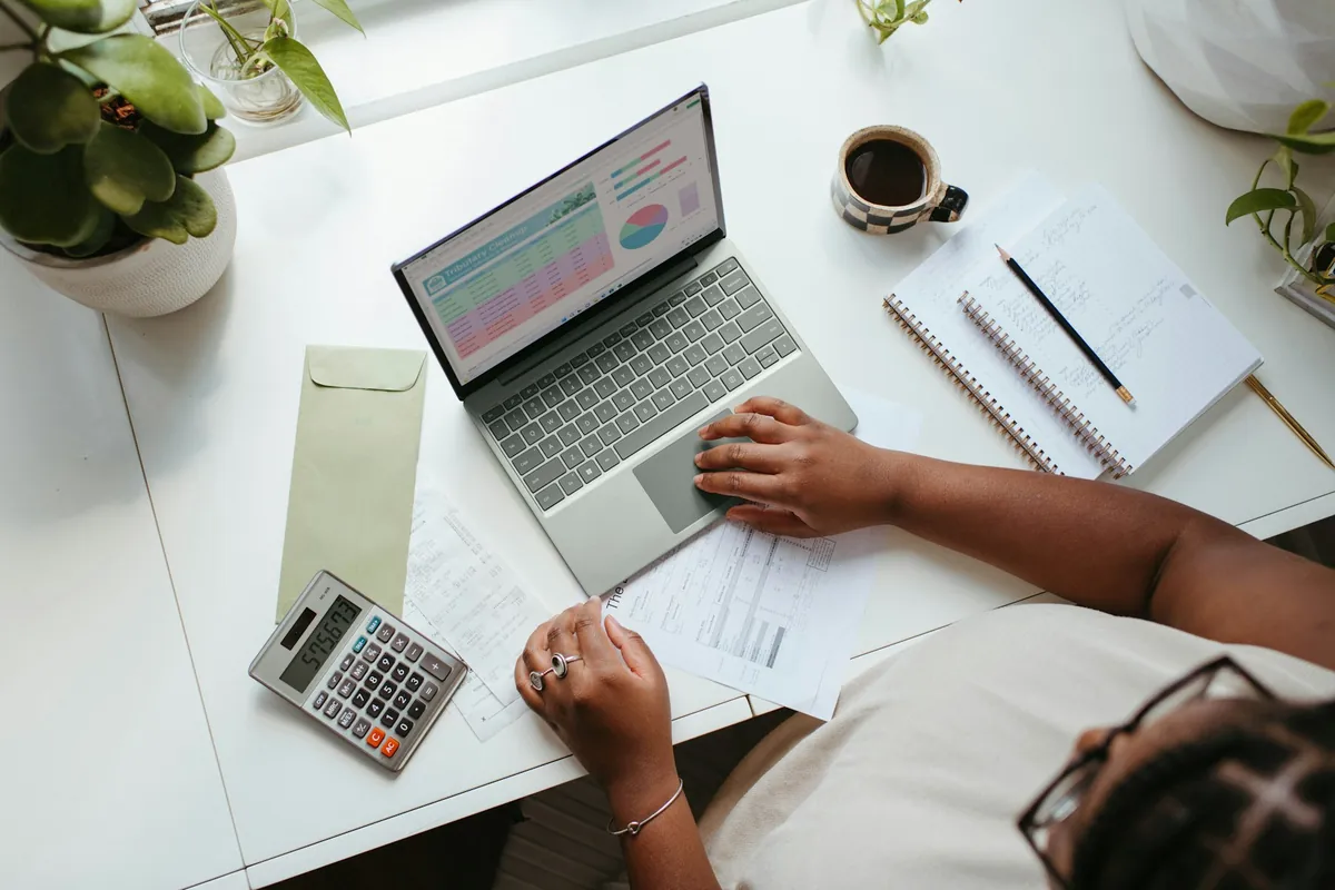 Illustrative stock photograph: Professional analysing a spreadsheet on a laptop with documents and calculator.