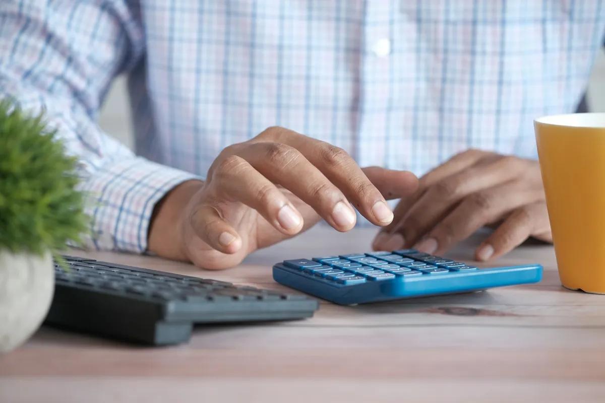 Illustrative stock photograph: Finance professional using a calculator at a desk.