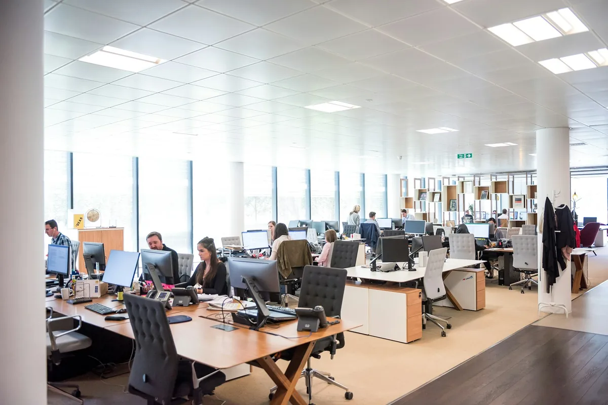 Illustrative stock photograph: Staff using computers in a bright enterprise office.
