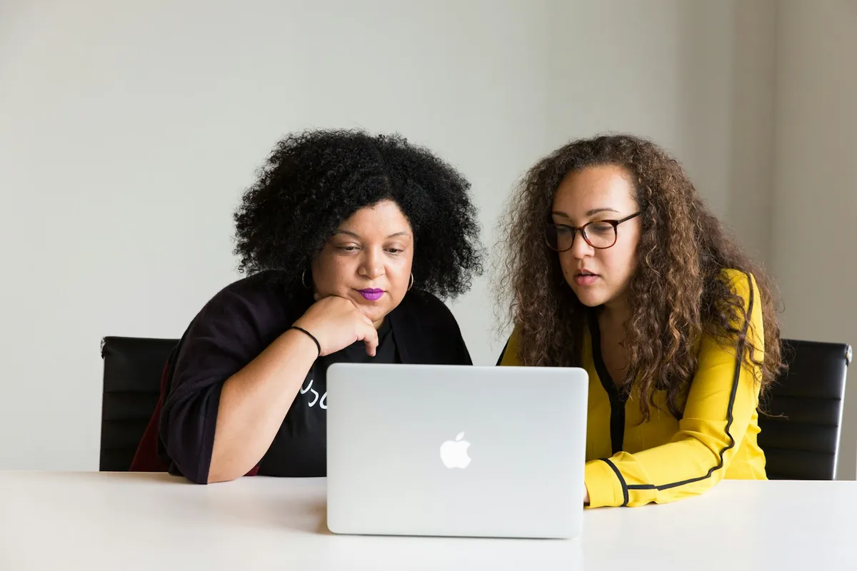 Colleague providing one-to-one support at a laptop