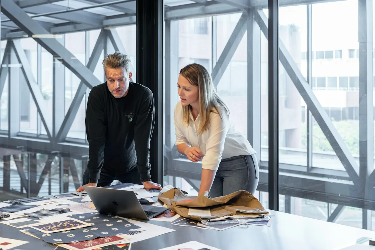 Two professionals reviewing business materials and a laptop in a bright office