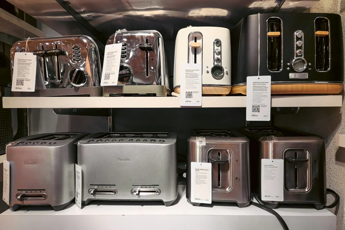 Retail shelves displaying electrical kitchen appliances with product and price labels