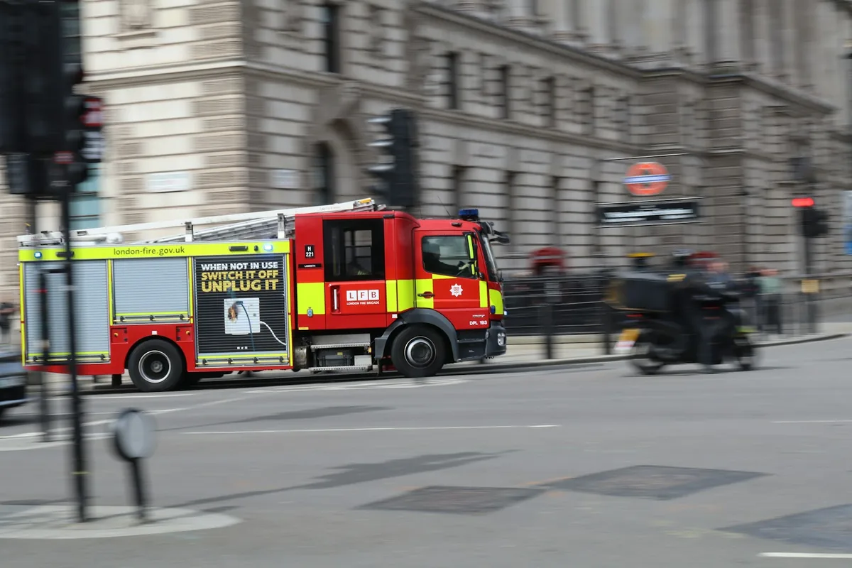 A red London Fire Brigade engine travelling along a London street