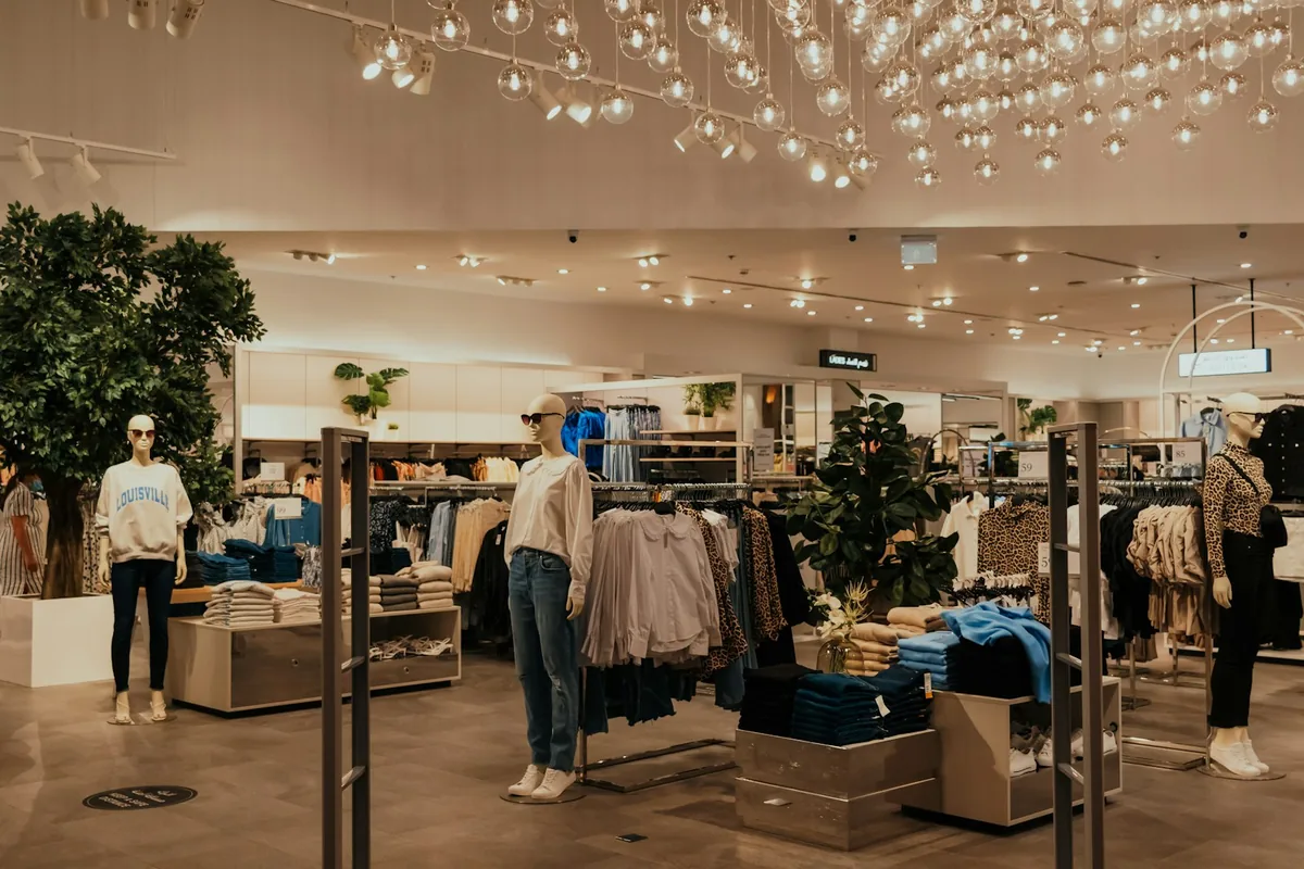 Warm modern retail clothing store with display rails and mannequins.