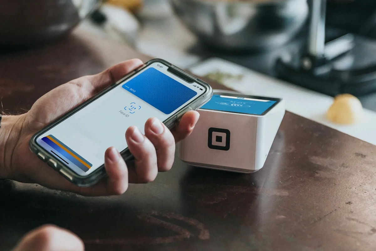 Customer holds a smartphone near a contactless payment terminal