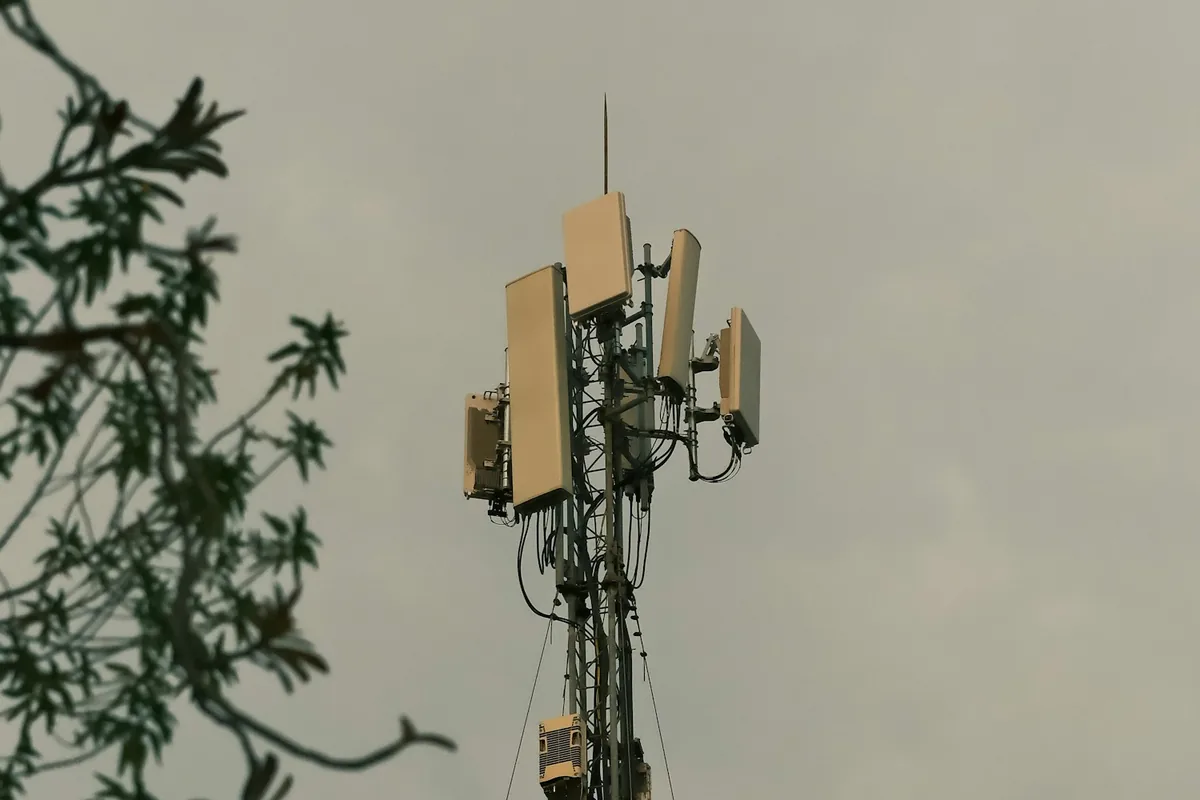 Telecommunications cell tower and antennas beneath a cloudy sky