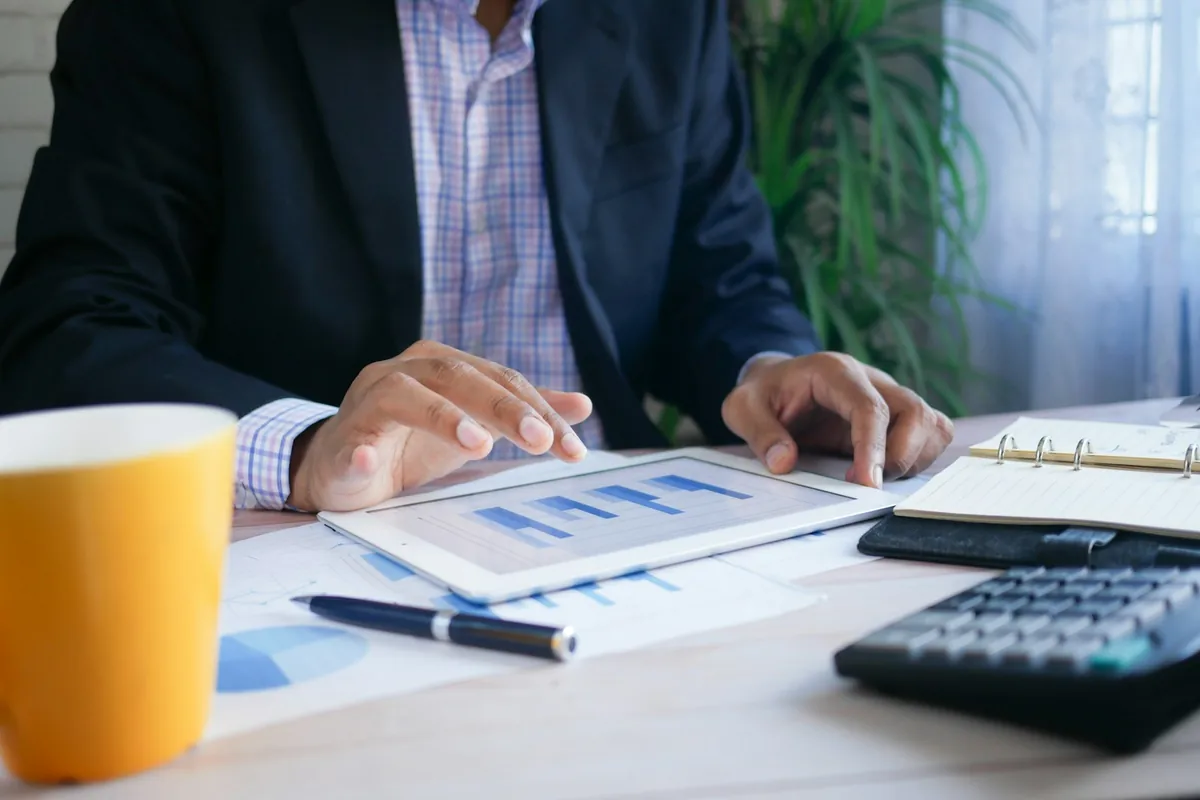 Finance professional reviewing financial charts with tablet and calculator