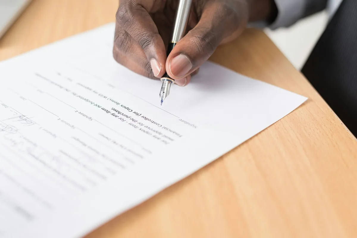 A business professional signs a document with a fountain pen.
