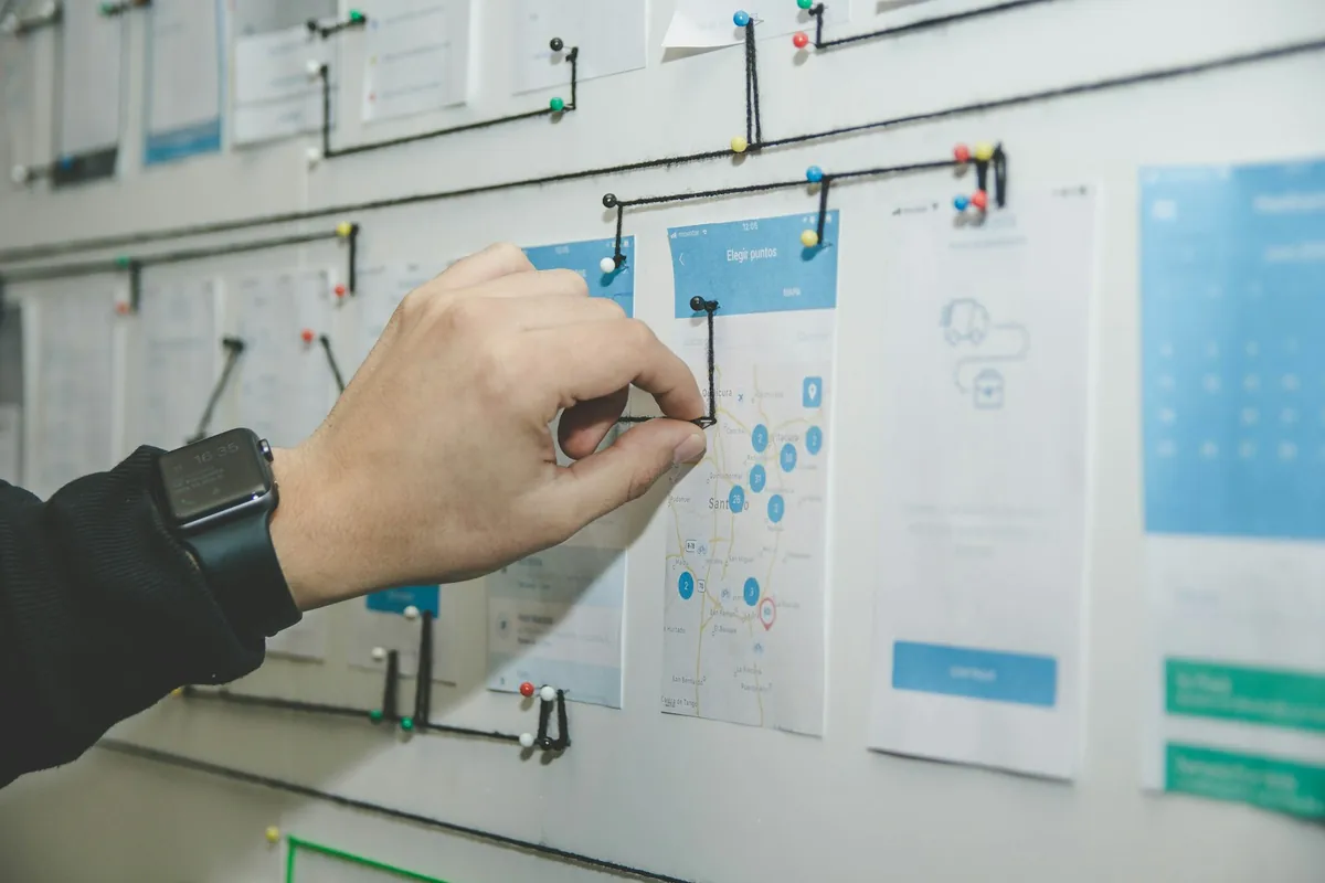 A hand updates a connected workflow board with project screens and pins.