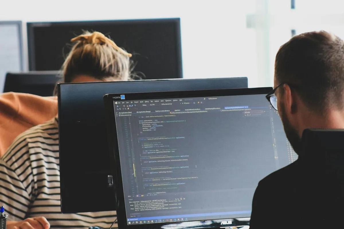 A technical colleague checks software code on a workstation monitor.