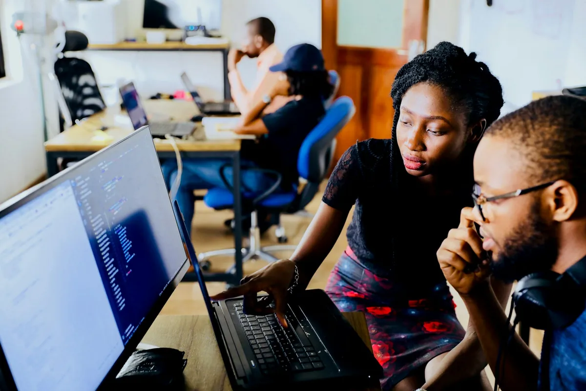 Two colleagues work together at a computer monitor during technical training.