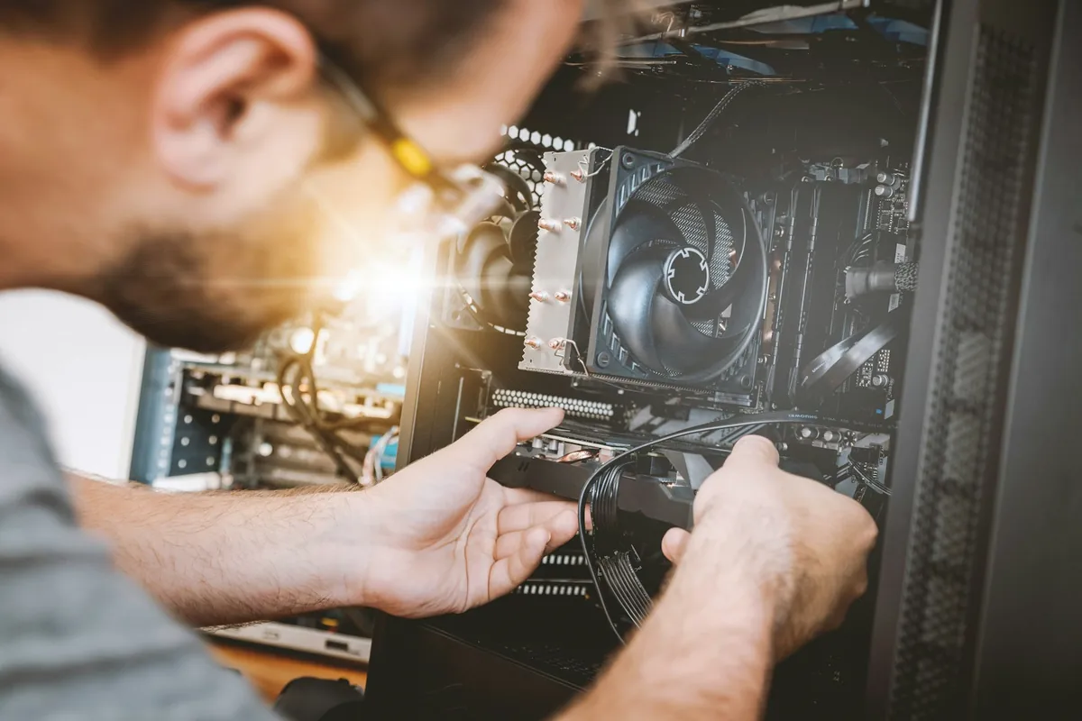 Technician installing computer hardware inside a desktop workstation