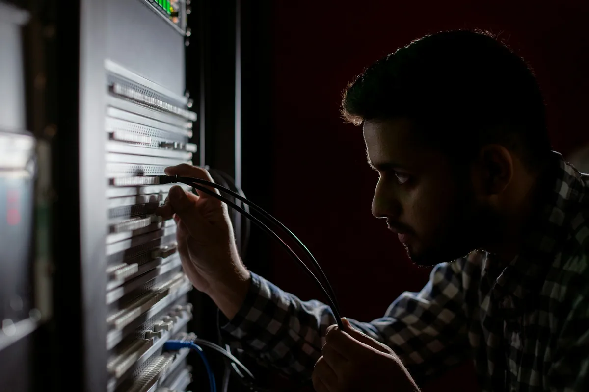 Engineer connecting cables to equipment in a technical workspace