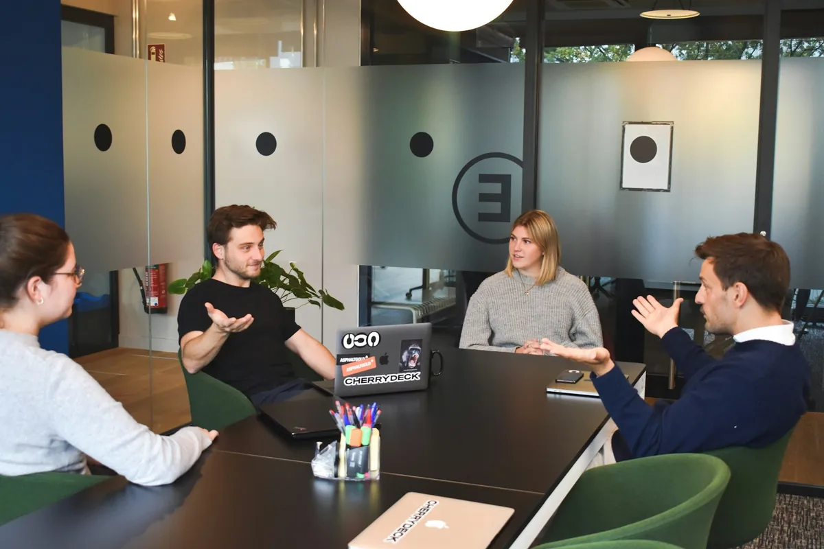 Four professionals collaborating around a black table in a modern office